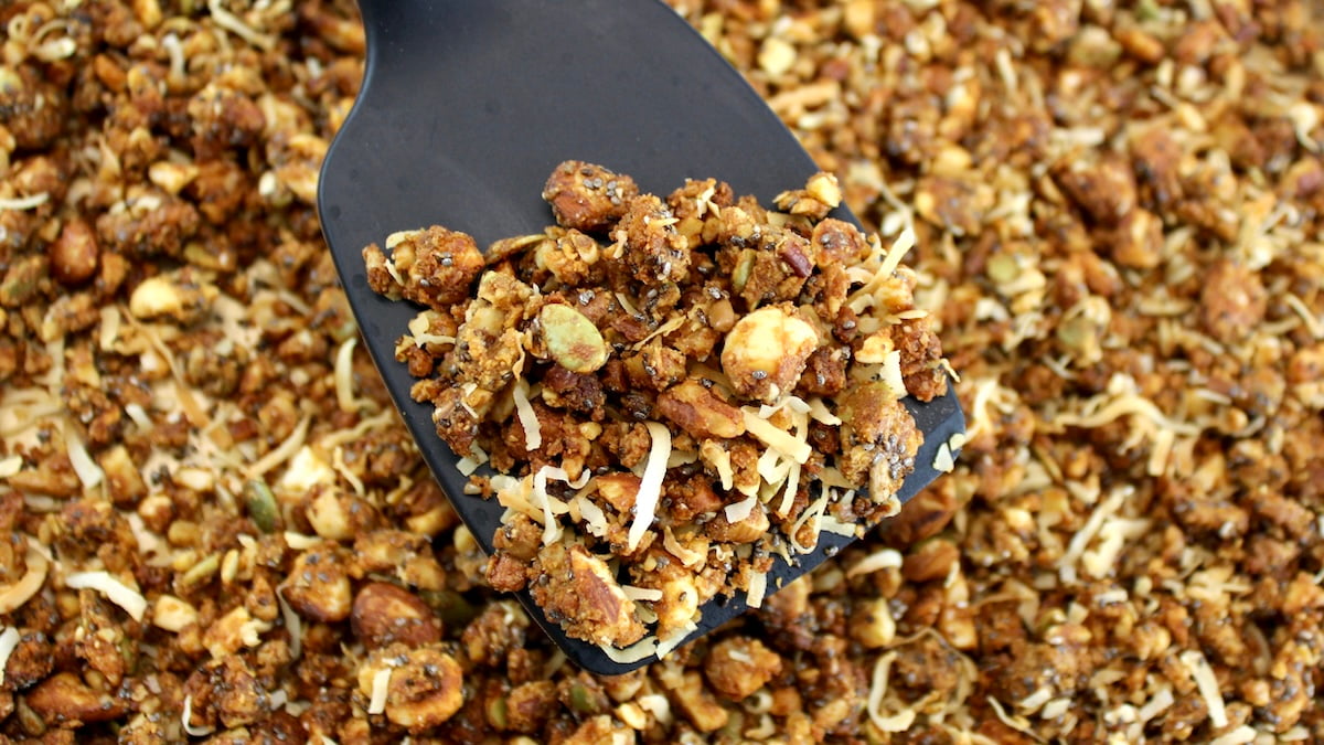 Keto Granola on baking sheet being mixed with spatula
