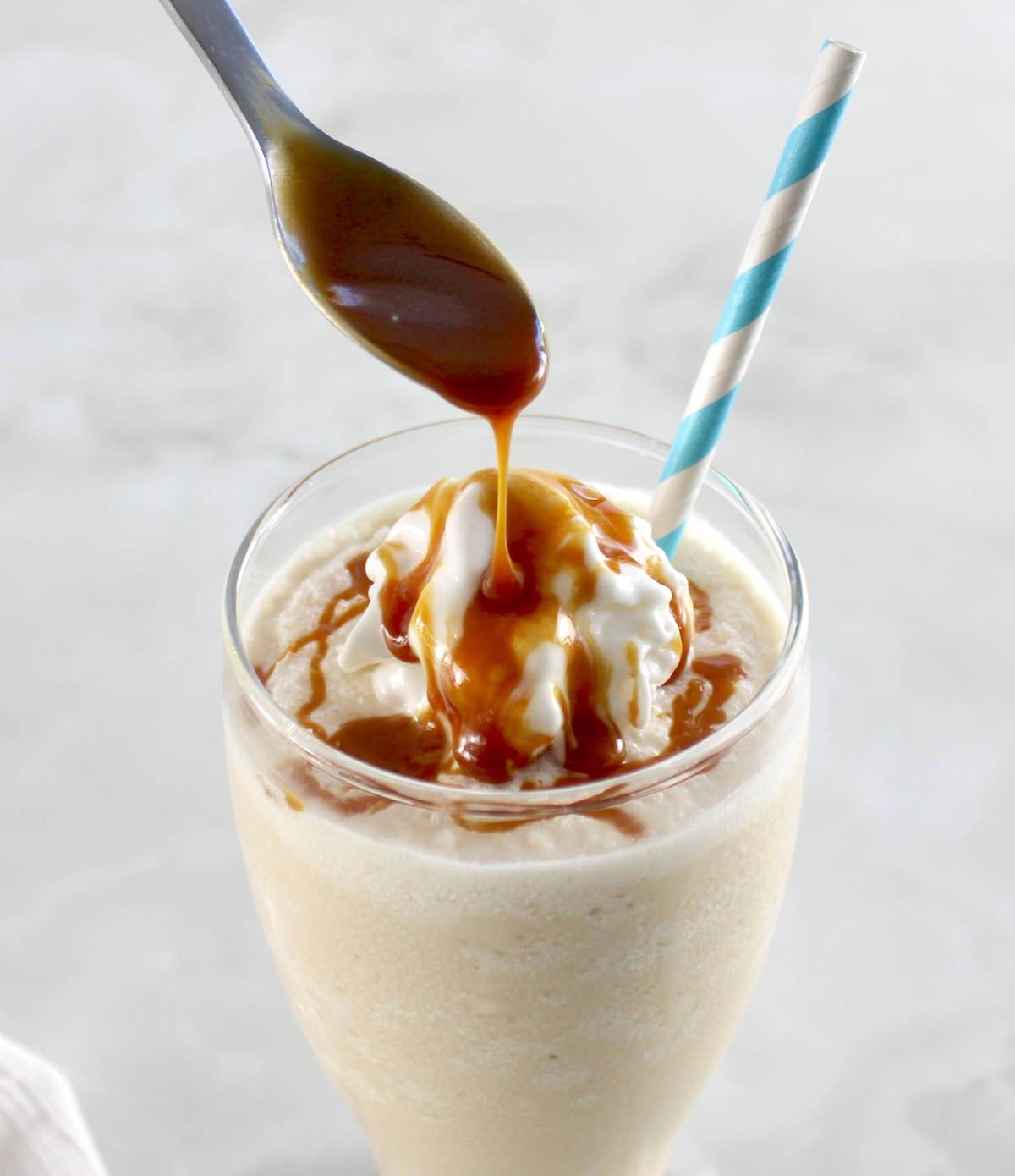 caramel being drizzled from spoon over top of Keto Salted Caramel Milkshake