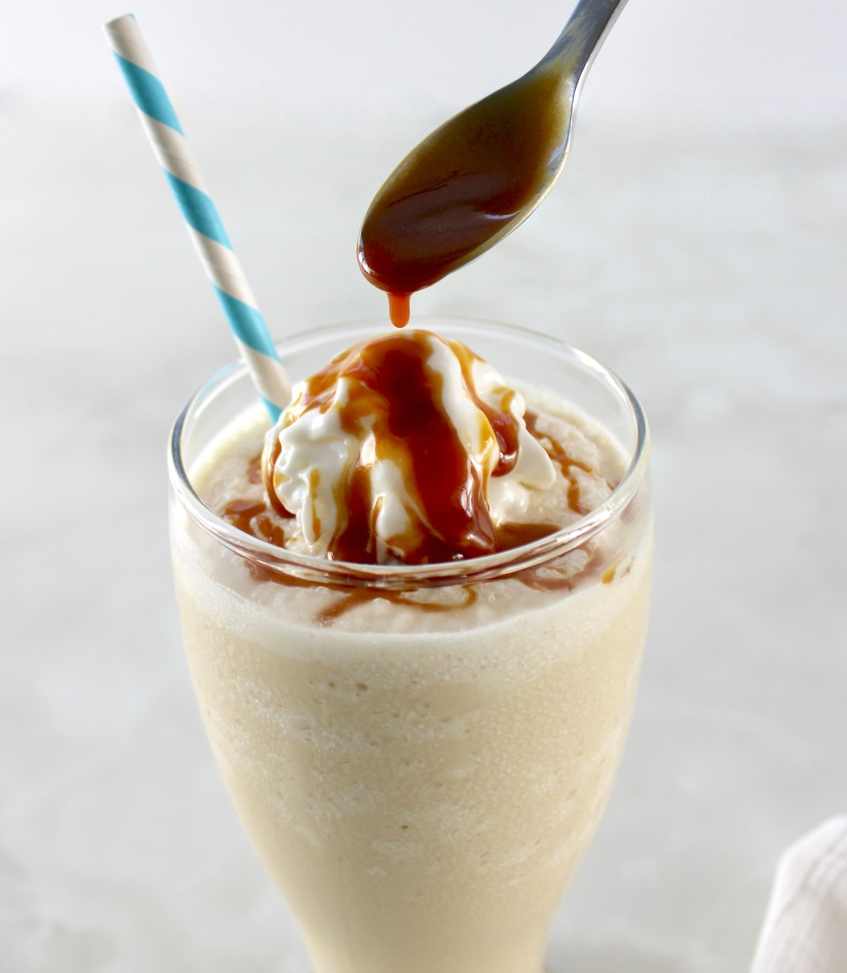 caramel being drizzled from spoon over top of Keto Salted Caramel Milkshake
