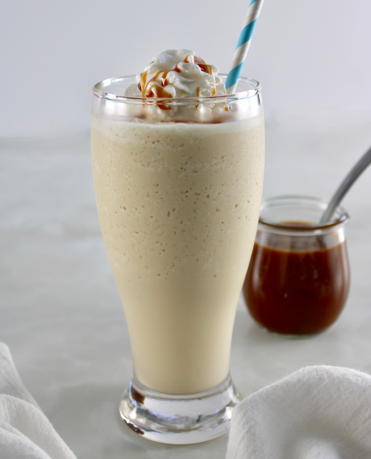 side view of Keto Salted Caramel Milkshake in glass with caramel in back