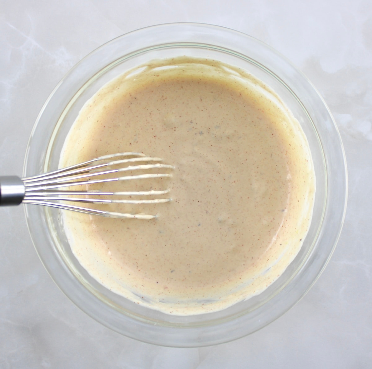 remoulade sauce in glass bowl with whisk