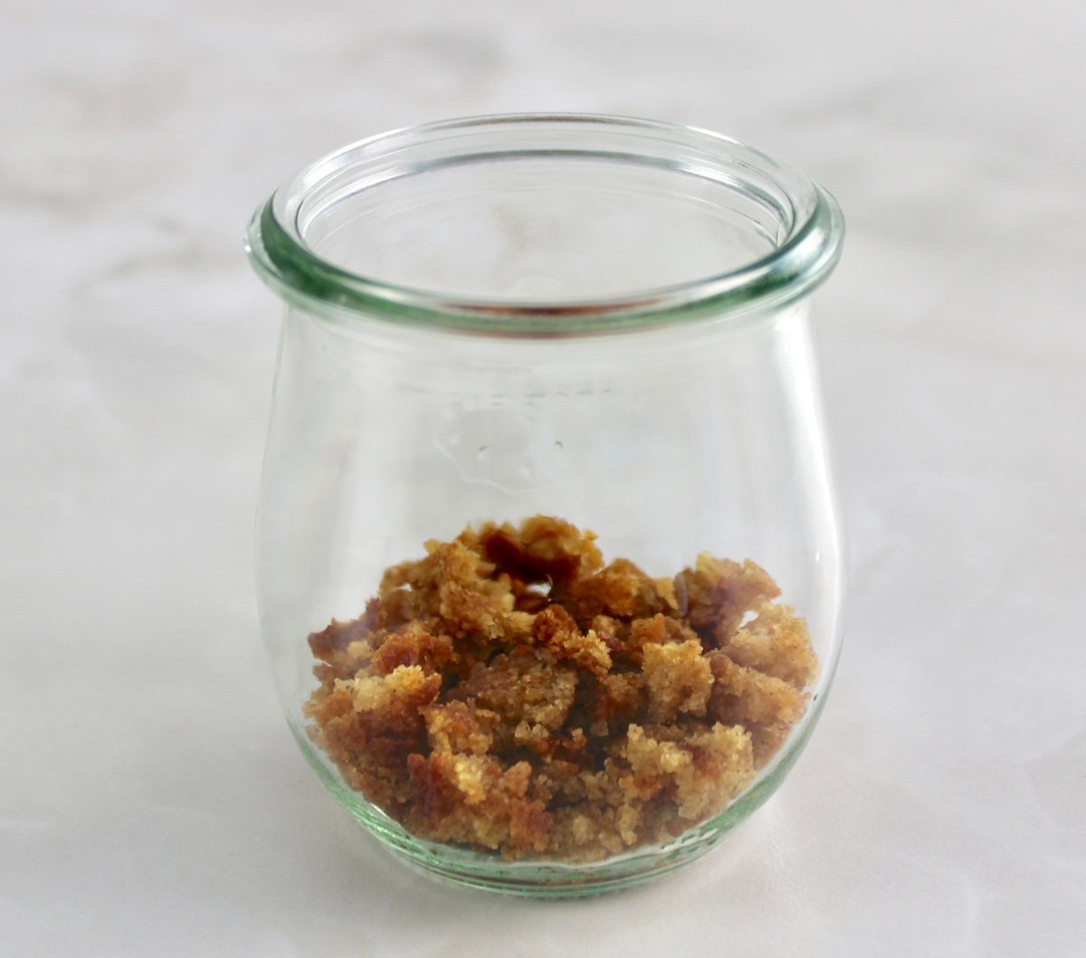 crumbled snickerdoodle cookies in bottom of open glass jar