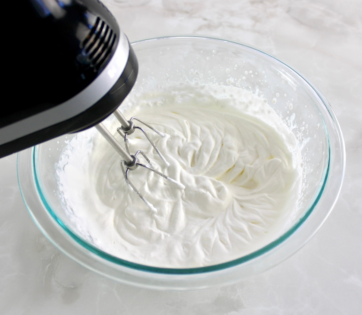 whip cream in glass bowl with hand mixer