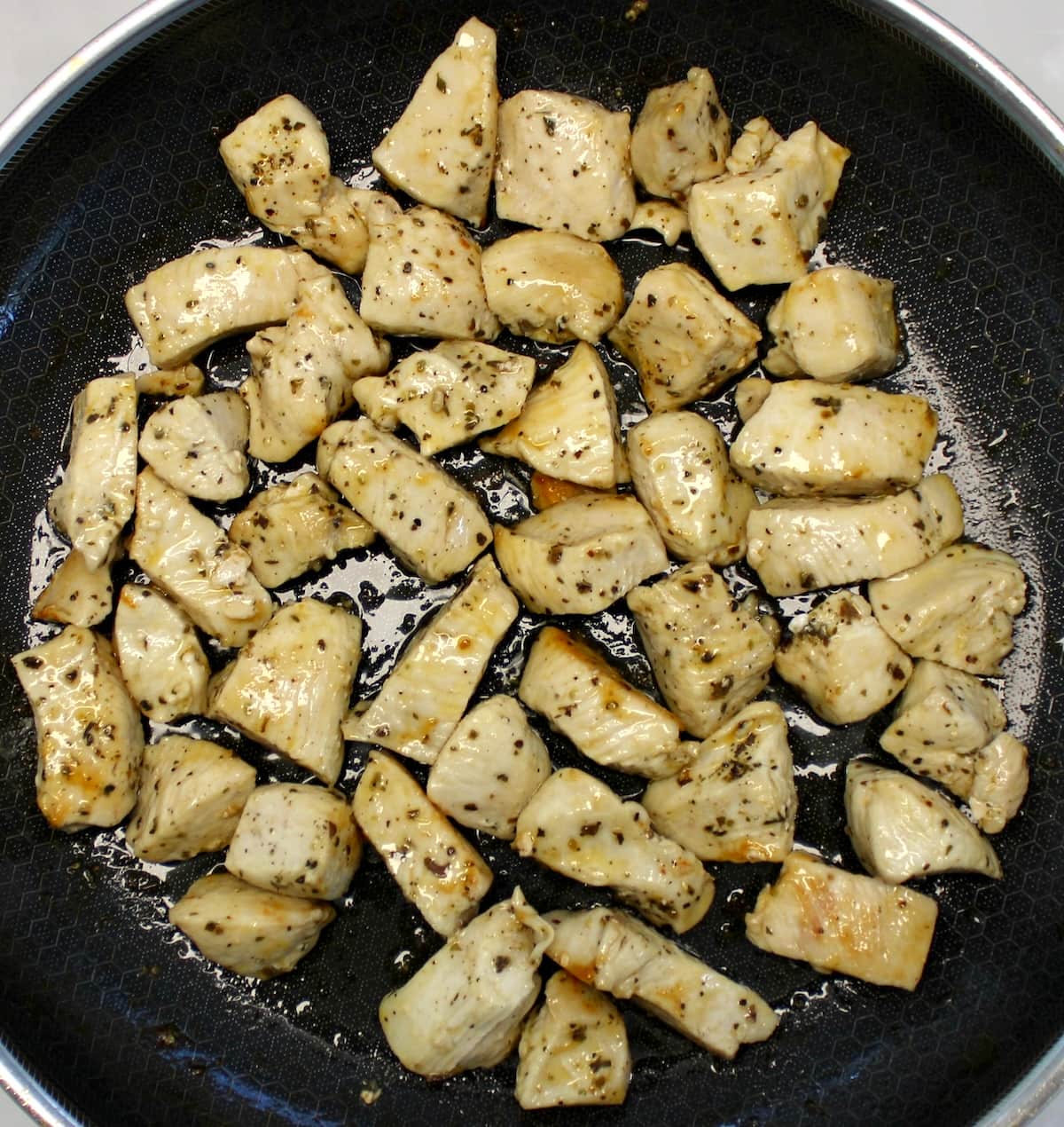 cooked chicken bites in skillet with dried herbs