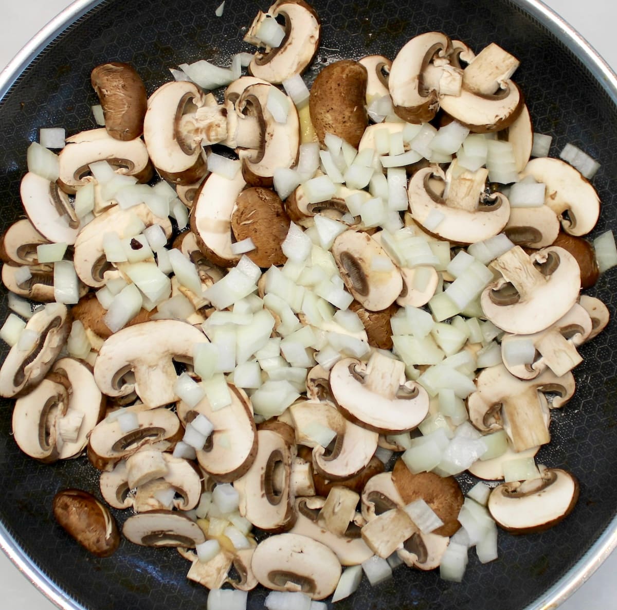 raw mushrooms and onions in skillet
