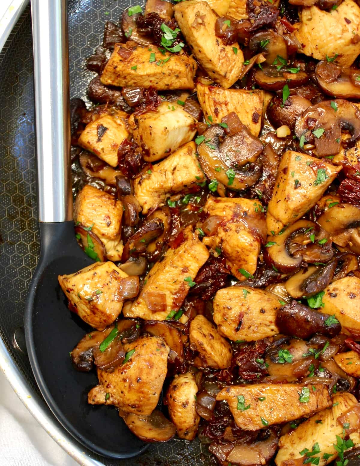 closeup of Marsala Mushroom Chicken Bites in skillet with serving spoon on side