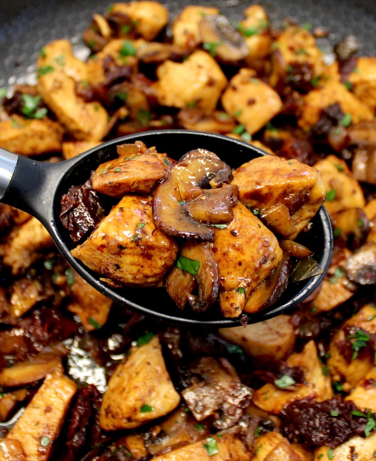 serving spoon full of Marsala Mushroom
Chicken Bites held over skillet