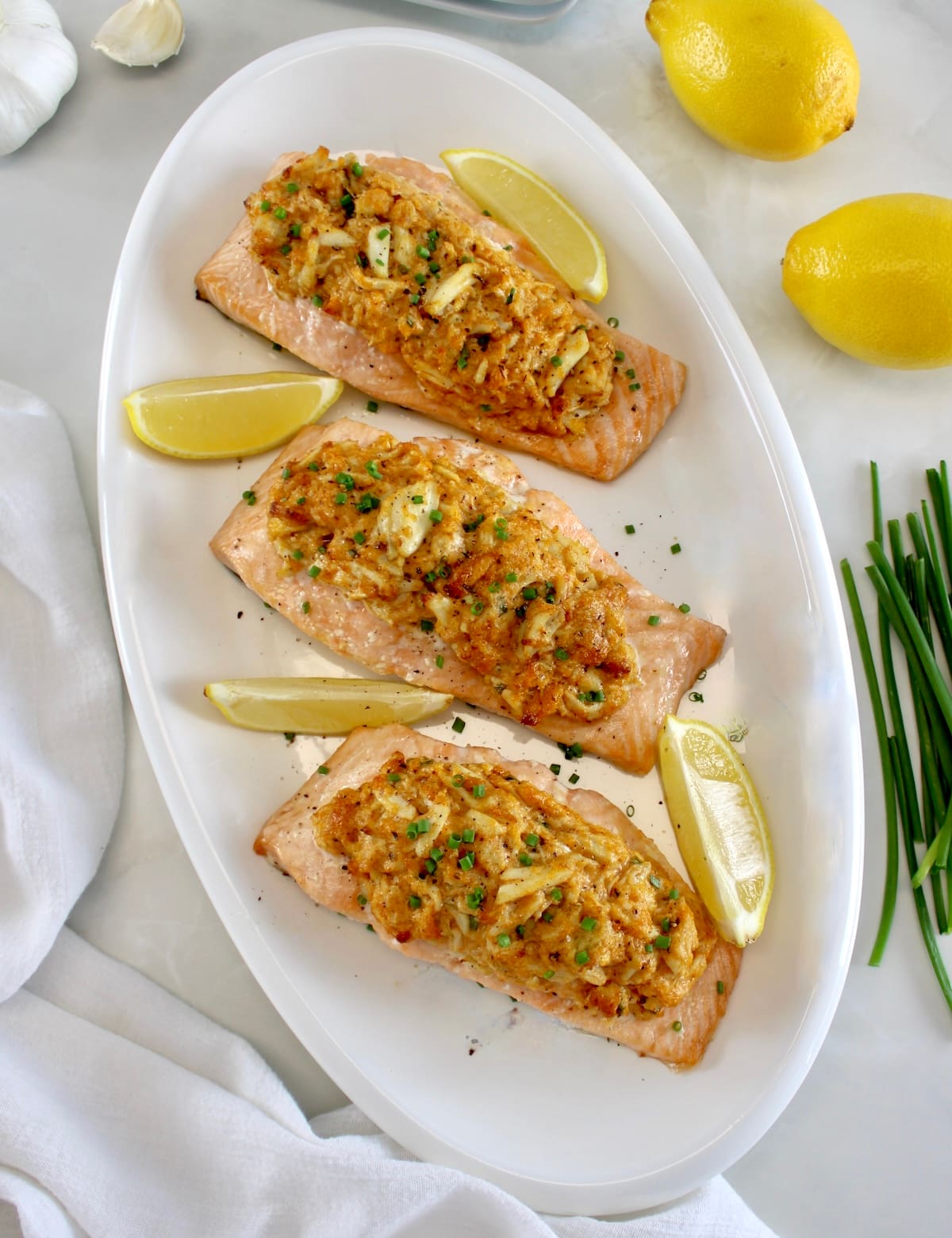 overhead view of 3 pieces of Cajun Crab Stuffed Salmon on white oval platter with lemon wedges