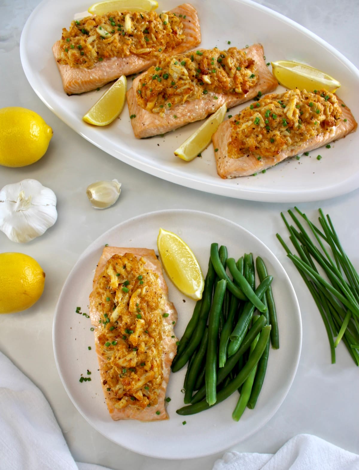 overhead view of Cajun Crab Stuffed Salmon on white plate with green beans and lemon wedge with more salmon in back
