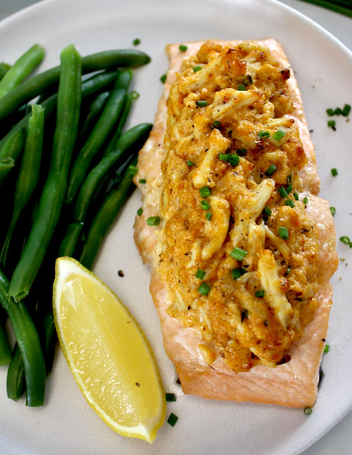 overhead closeup of Cajun Crab Stuffed Salmon on white plate with green beans and lemon wedge