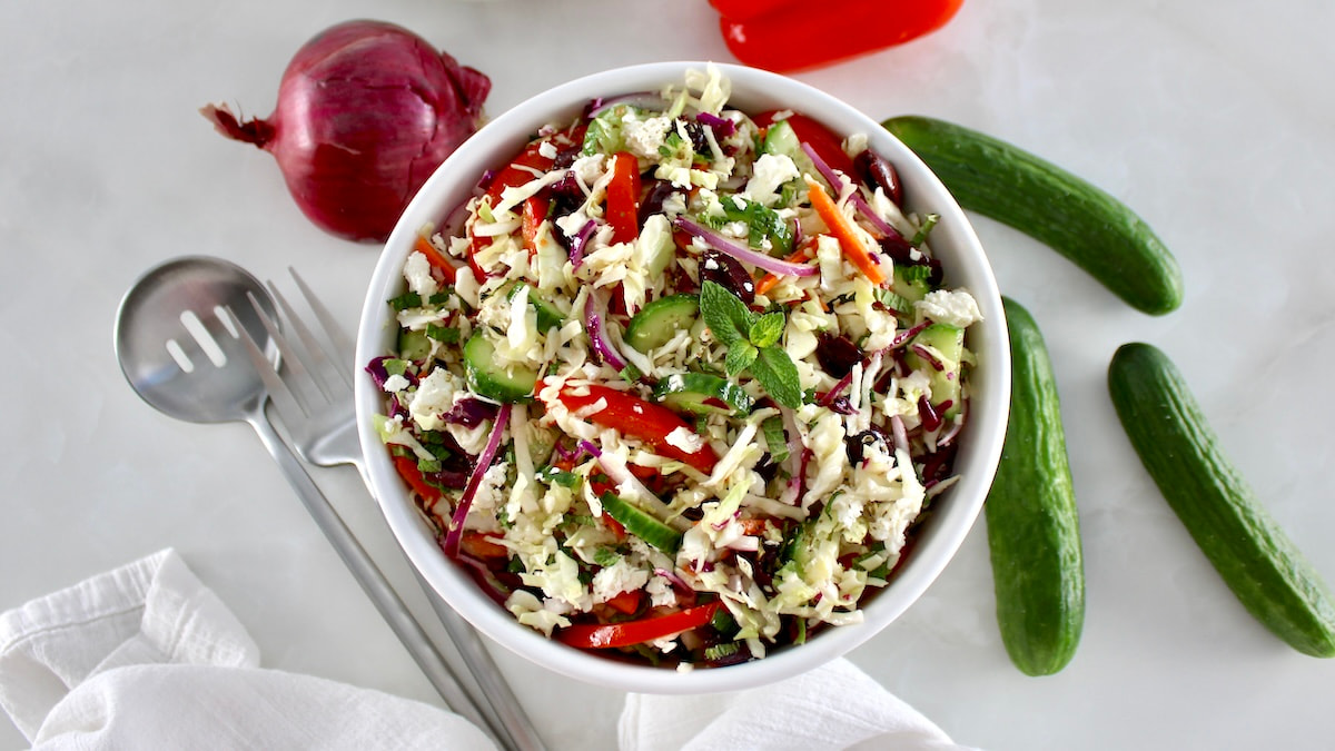 overhead view of Greek Coleslaw in white bowl with veggies around