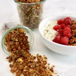Keto Granola spilling out of jar with raspberry yogurt bowl in back
