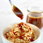 Keto Salted Caramel Cheesecake Mousse in blue bowl with caramel dripping off spoon over it