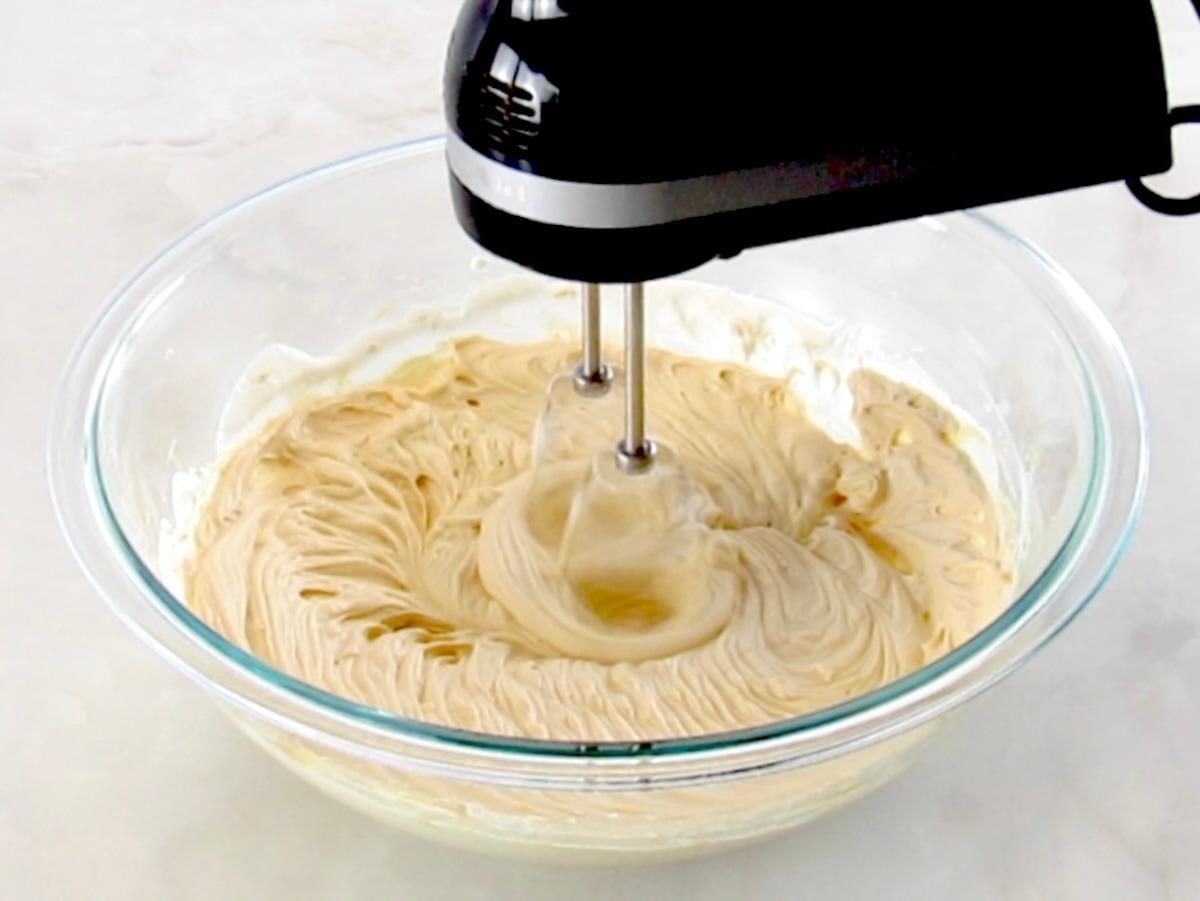 Keto Salted Caramel Cheesecake Mousse in glass bowl being mixed with hand mixer