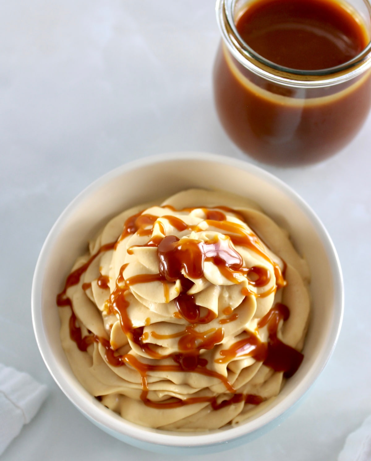overhead view of Keto Salted Caramel Cheesecake Mousse in bowl with caramel in back