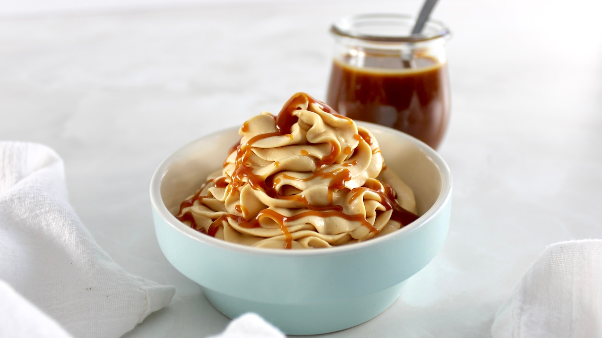 Keto Salted Caramel Cheesecake Mousse in blue bowl with caramel in back