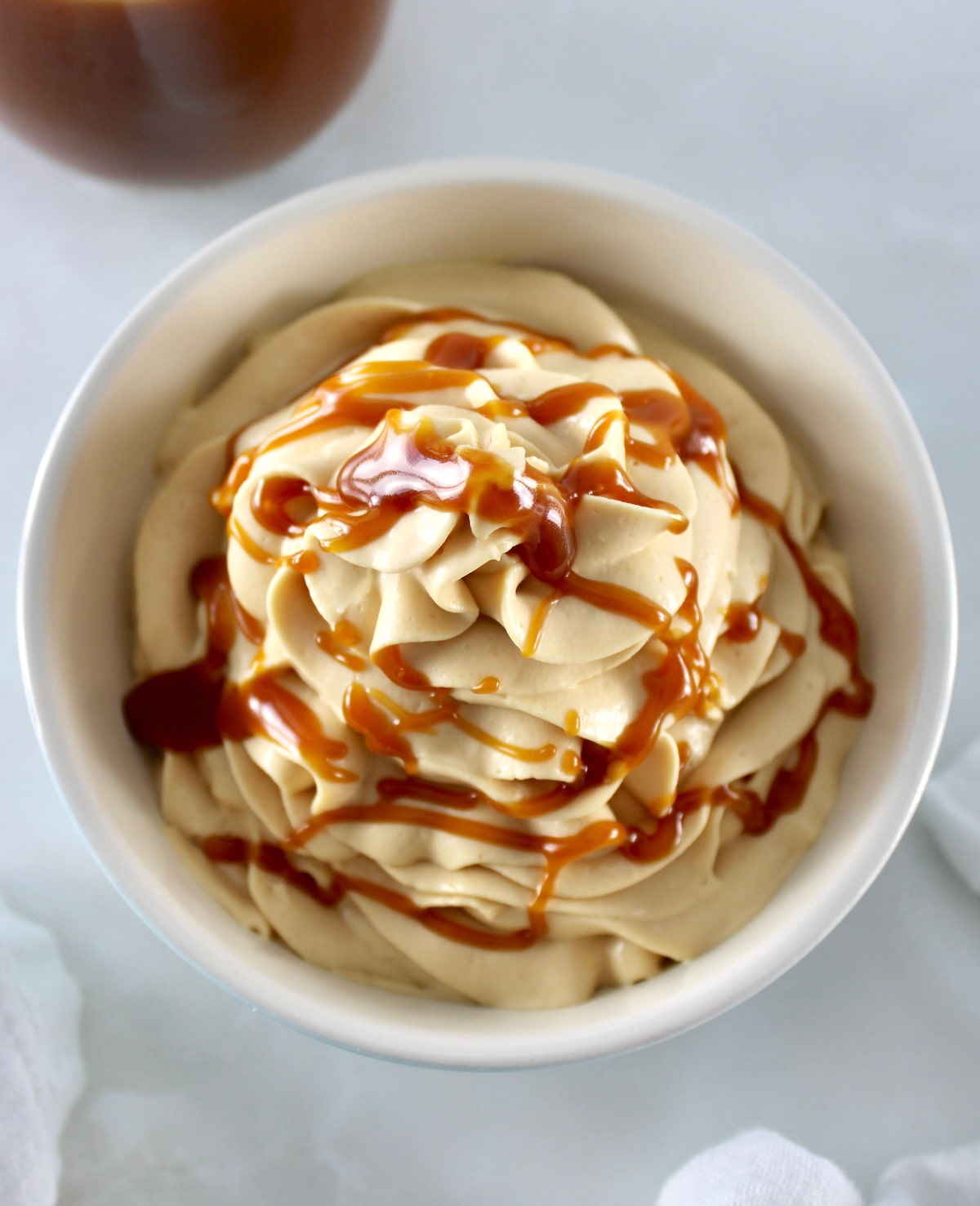overhead view of  Keto Salted Caramel Cheesecake Mousse in bowl with caramel in back