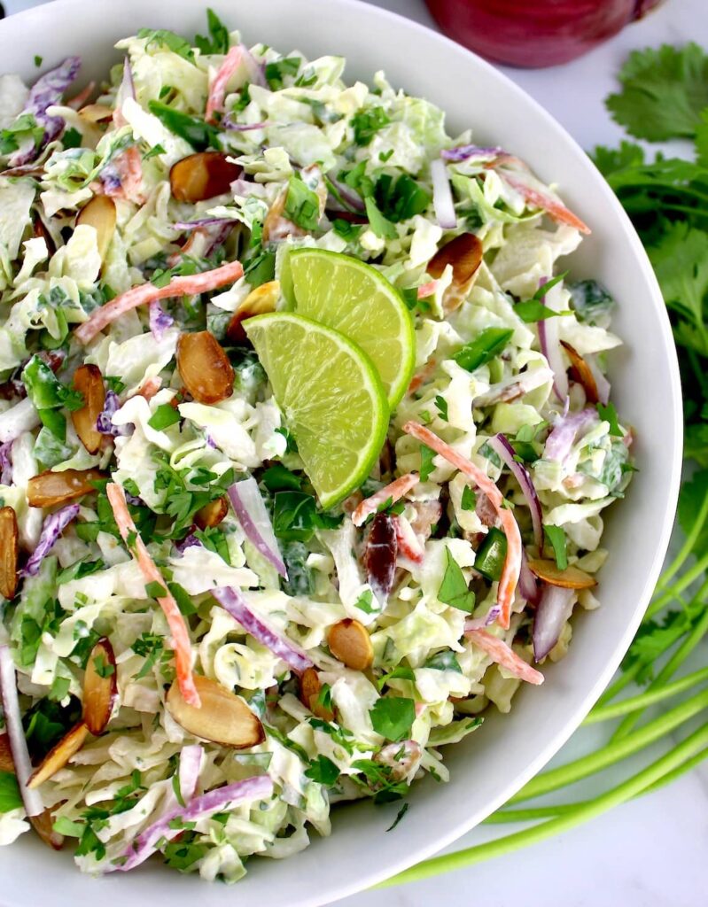 Cilantro Lime Coleslaw in white bowl with 2 lime slices on top