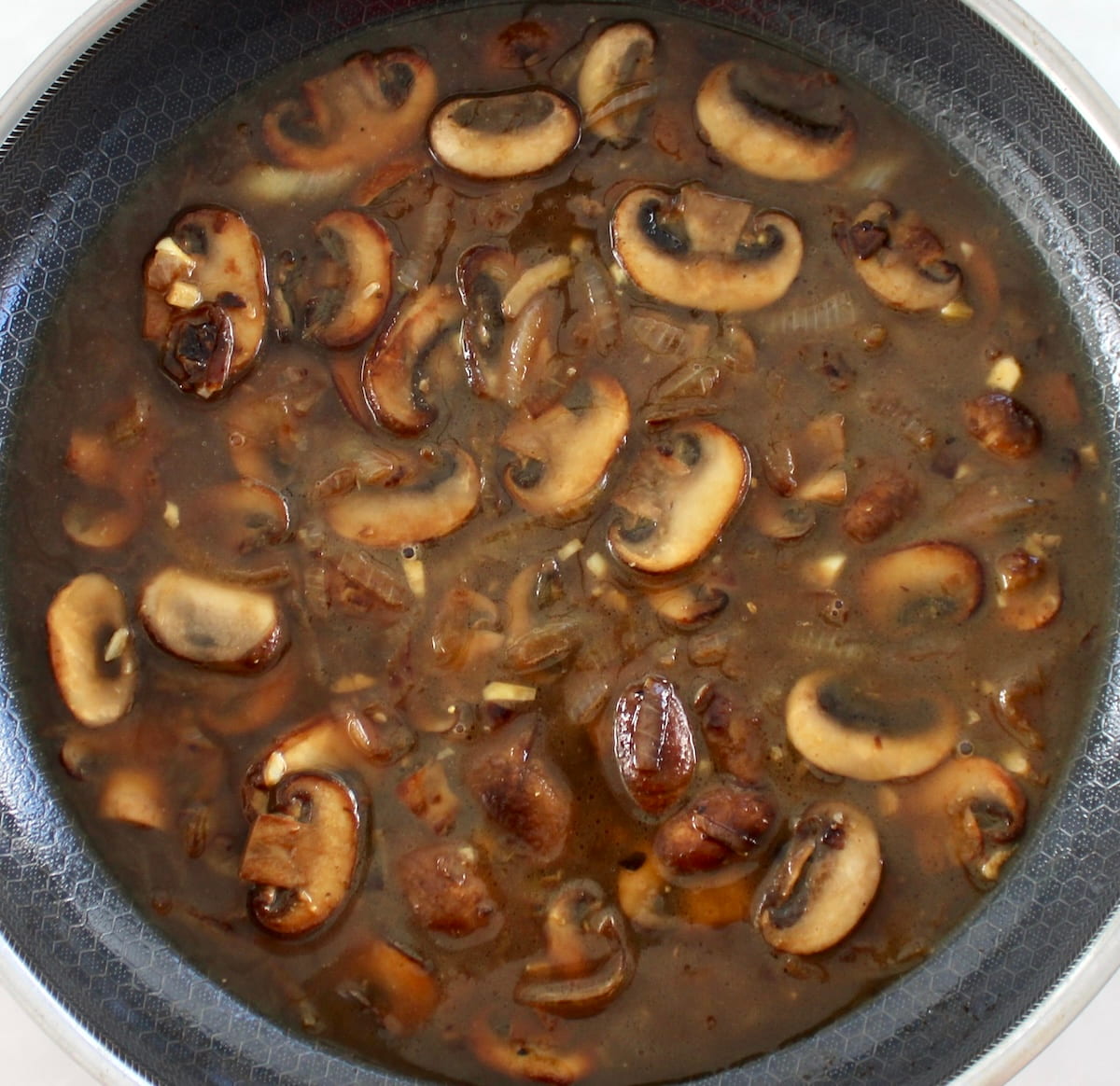 mushrooms and onions with beef broth in skillet