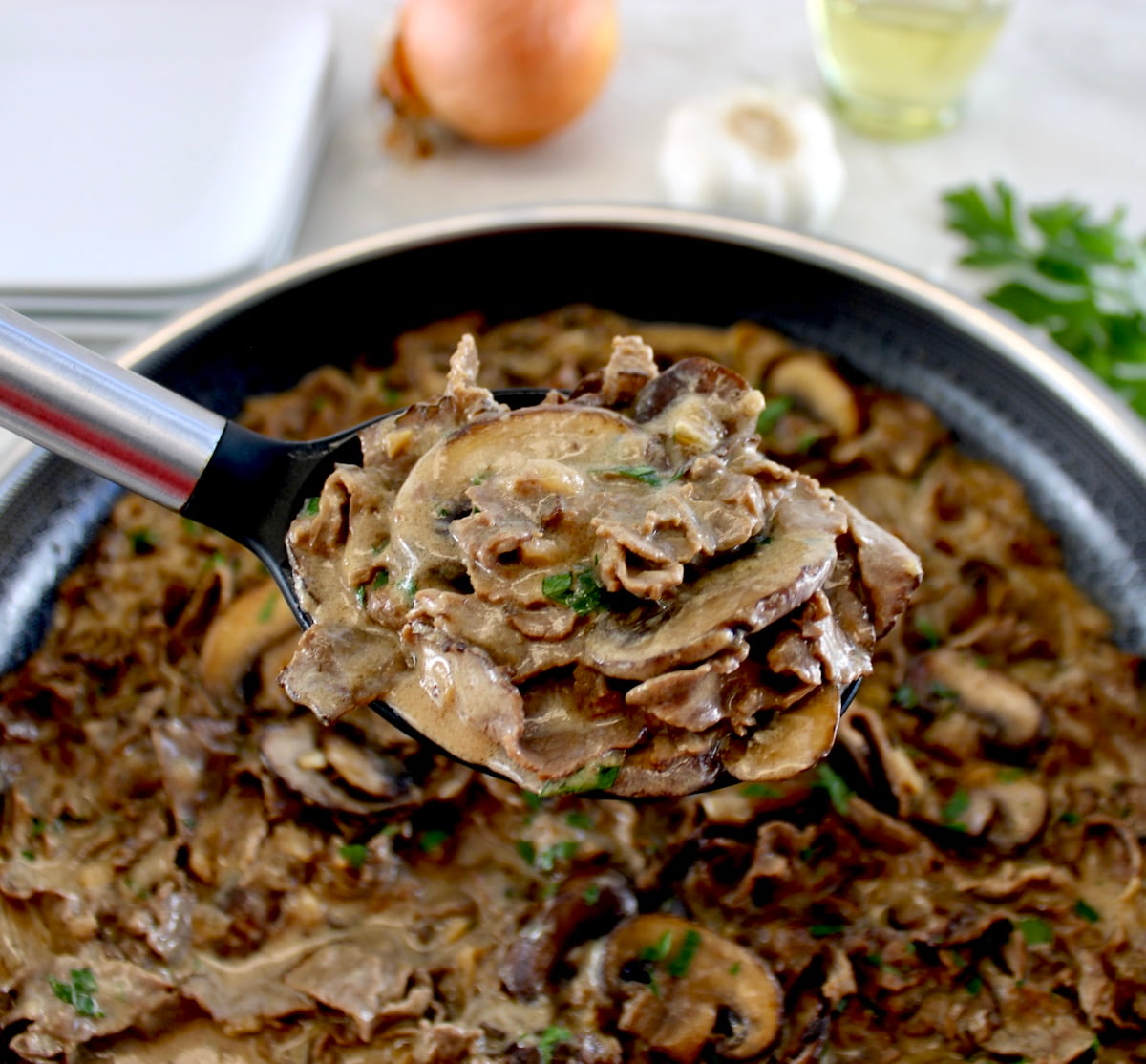 ladle full of Easy Beef Stroganoff held up over skillet