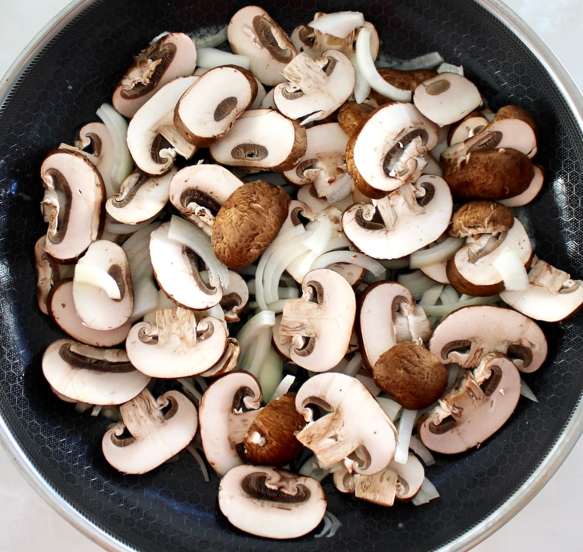 raw sliced mushrooms and onions in skillet
