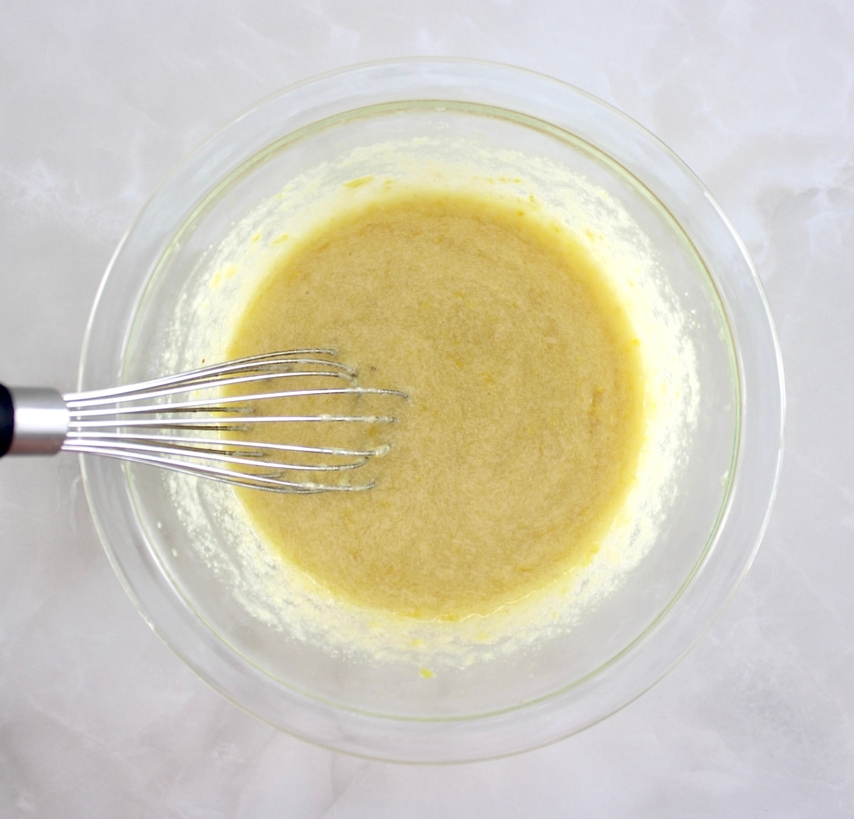 Keto Lemon Mug Cake batter in glass bowl with whisk