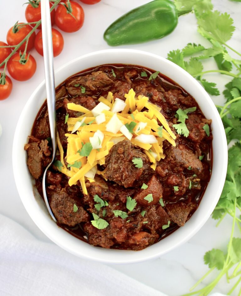 overhead view of Slow Cooker Texas Chili in white bowl with spoon and cheese on top