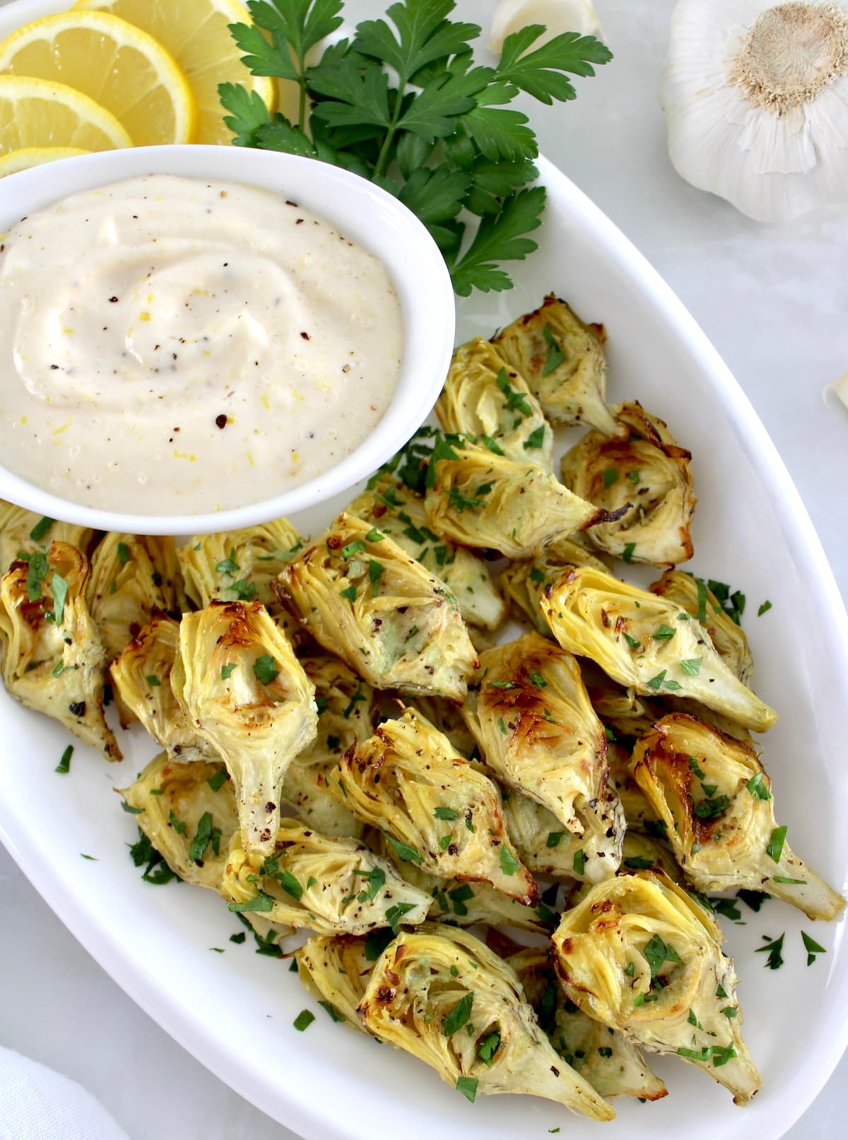 Air Fryer Artichoke Hearts on white platter with garlic aioli