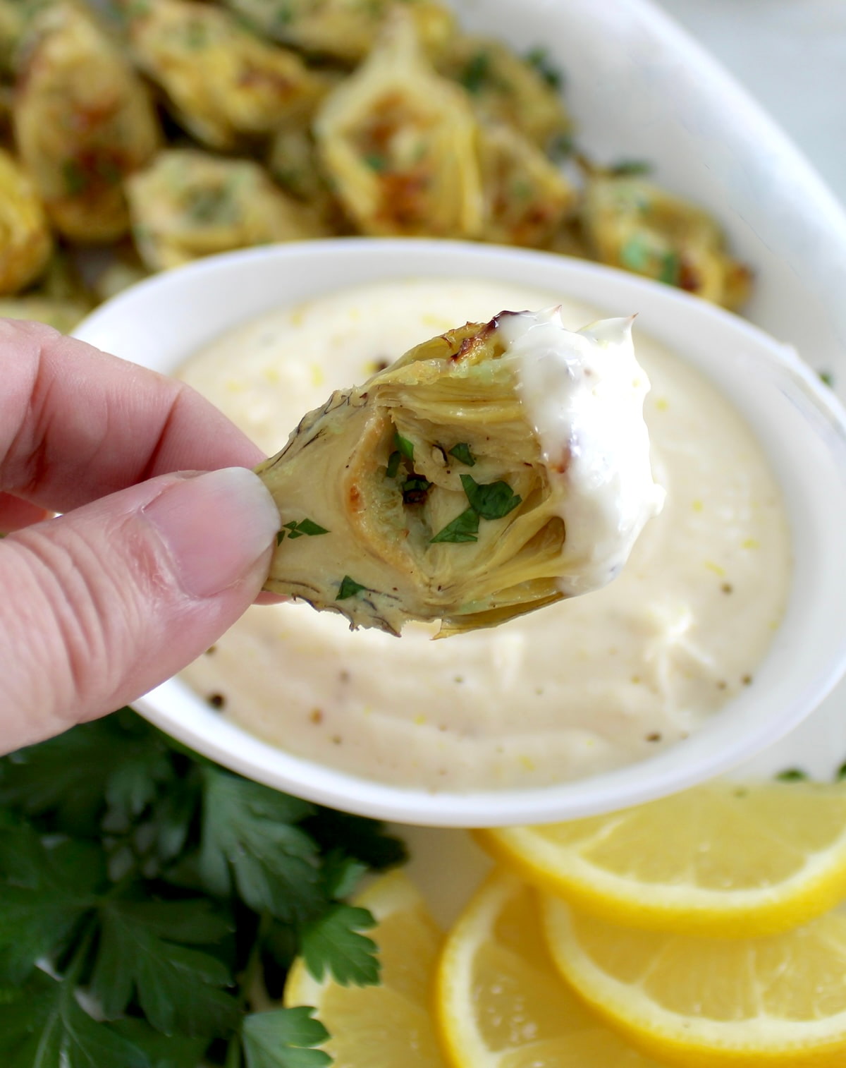 holding artichoke heart dipped in garlic aioli