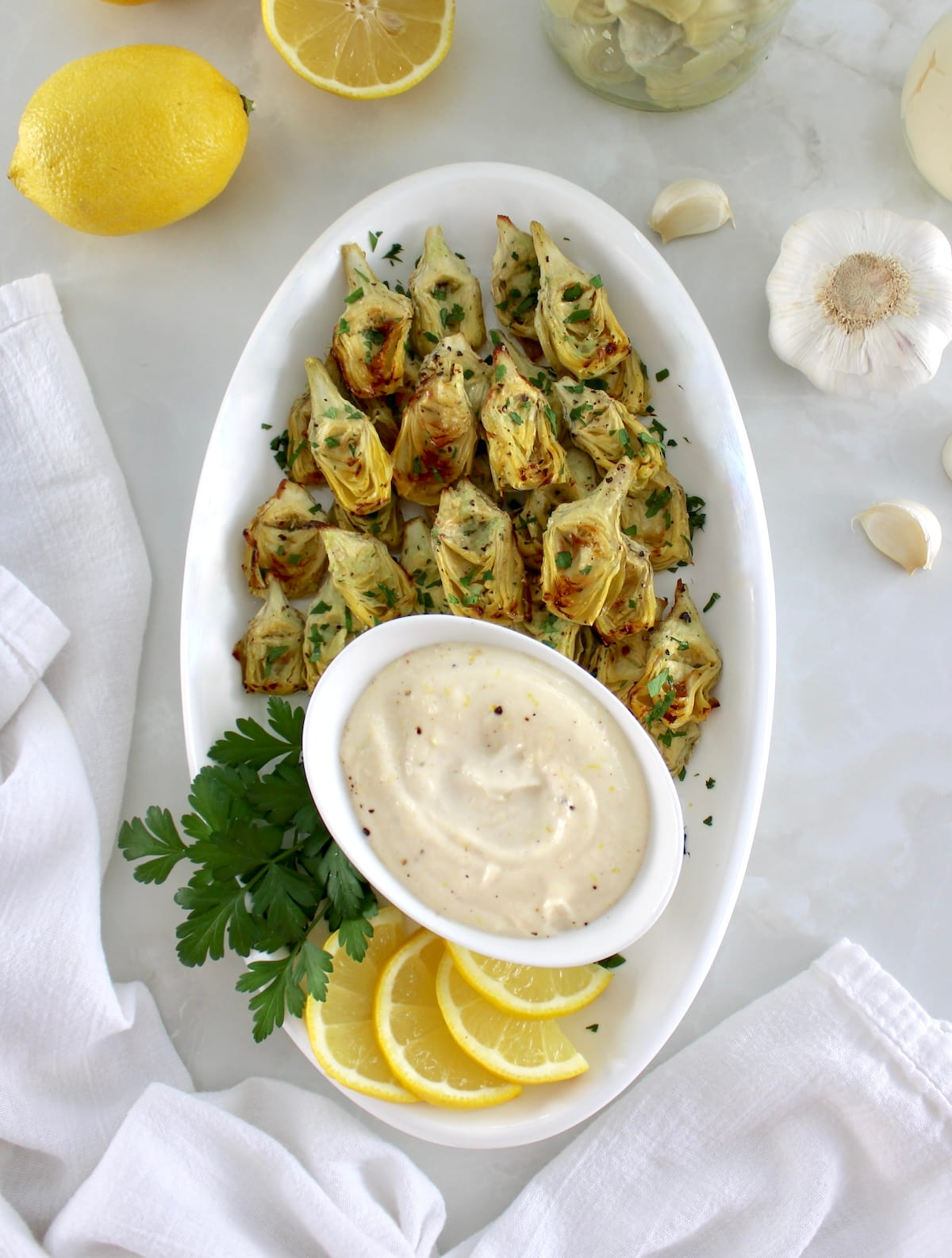 overhead view of Air Fryer Artichoke Hearts on white oval platter with garlic aioli