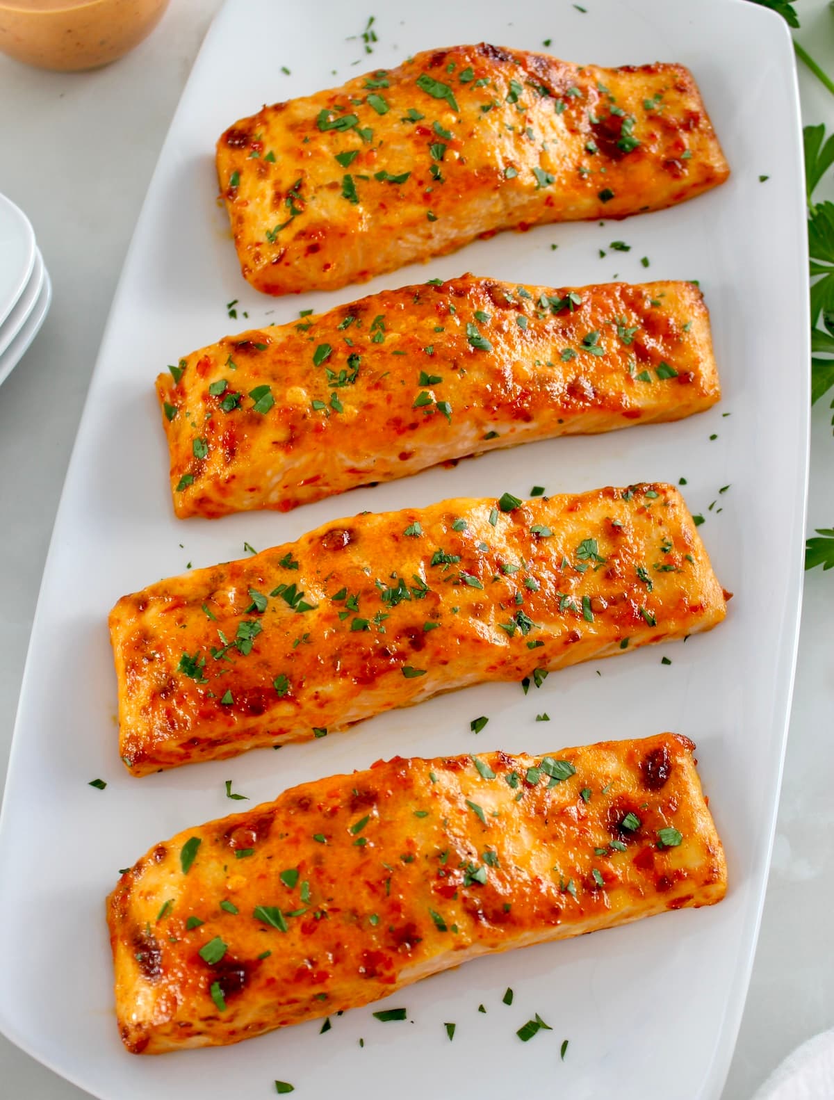 overhead view of 4 pieces of Bang Bang Salmon on white platter