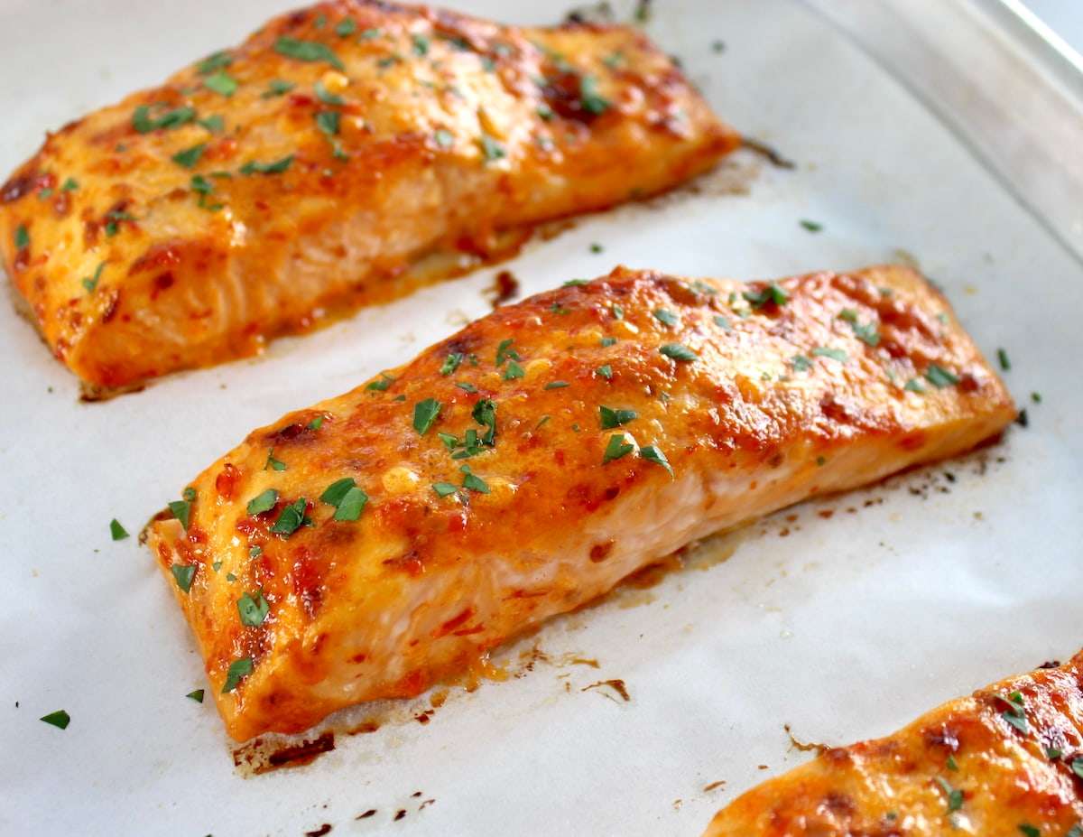 baked Bang Bang Salmon on parchment lined baking sheet