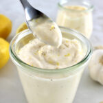 Easy Garlic Aioli in spoon held up over open glass jar