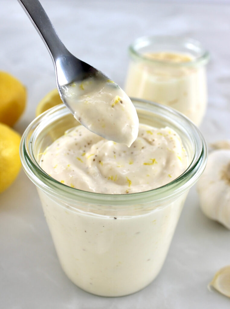 Easy Garlic Aioli in spoon held up over open glass jar