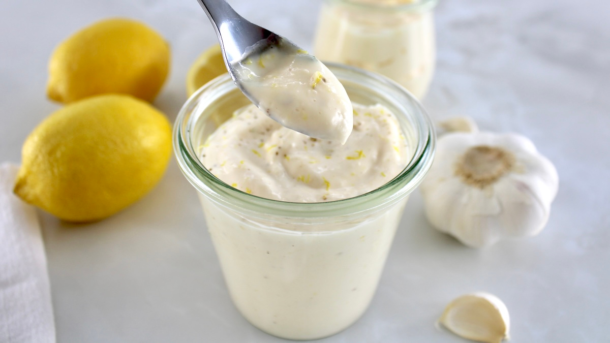 spoonful of Easy Garlic Aioli held up over open glass jar