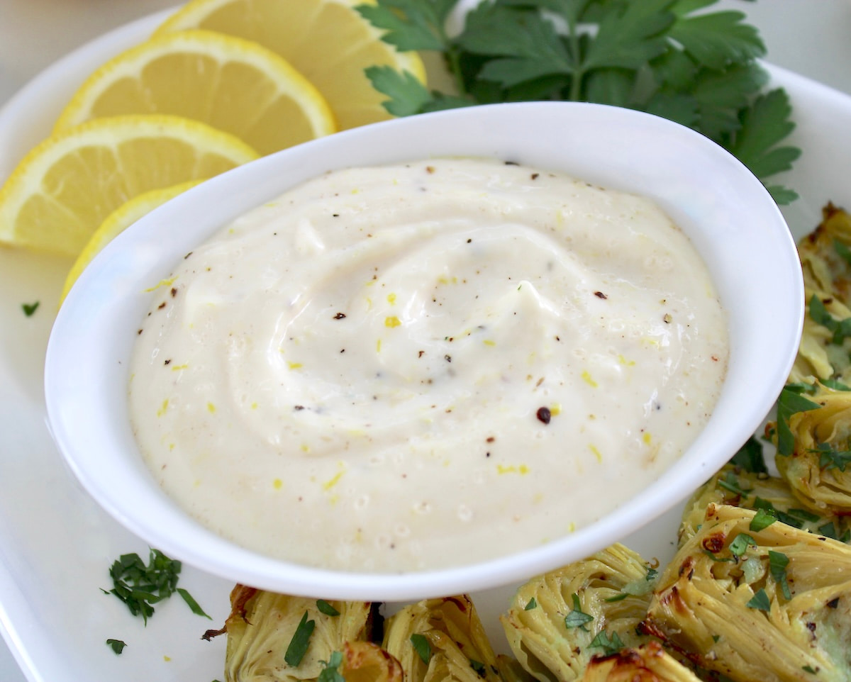Easy Garlic Aioli in white bowl with lemons on side