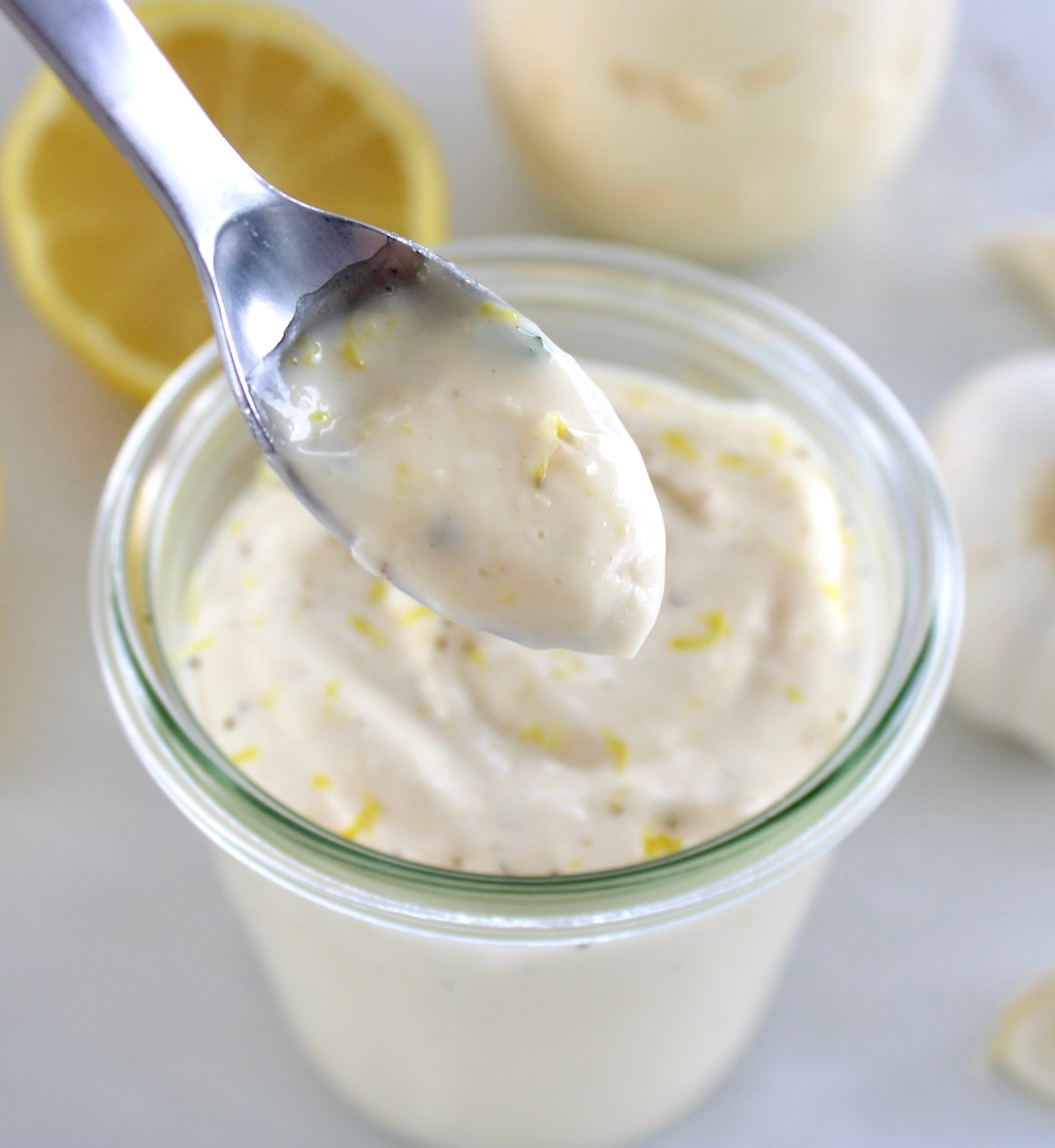 Easy Garlic Aioli in spoon held up over open glass jar