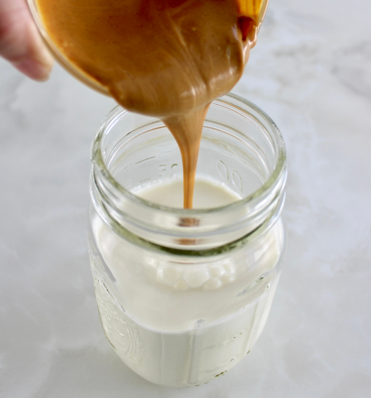 peanut butter being poured into mason jar with heavy cream
