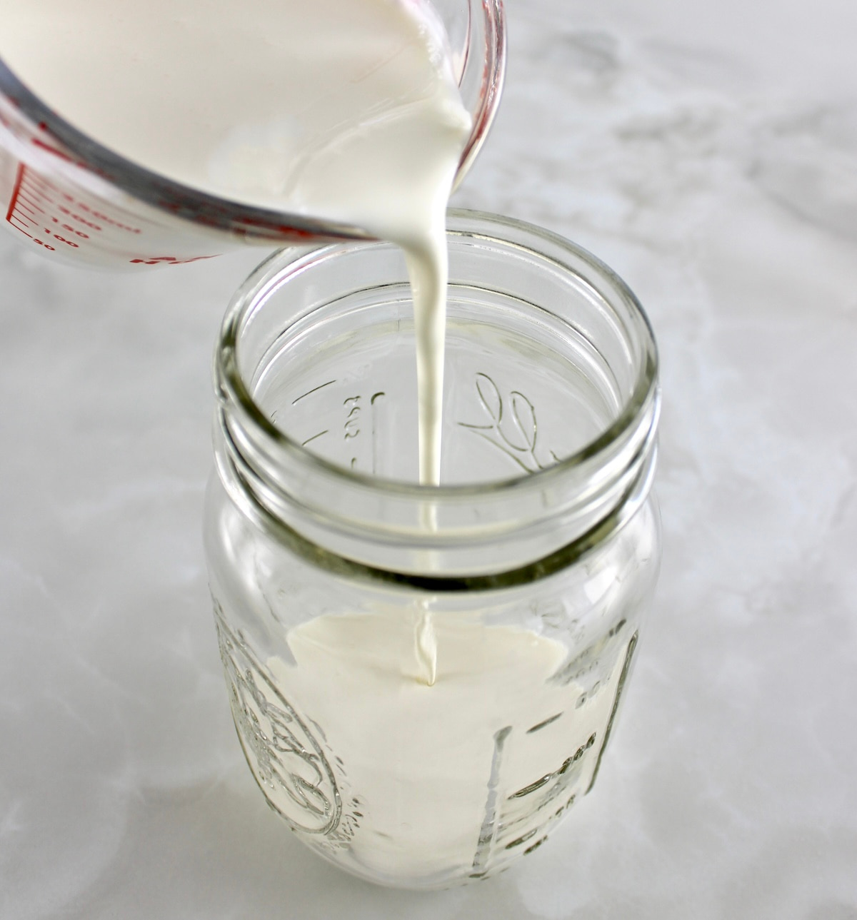 pouring heavy cream into a mason jar