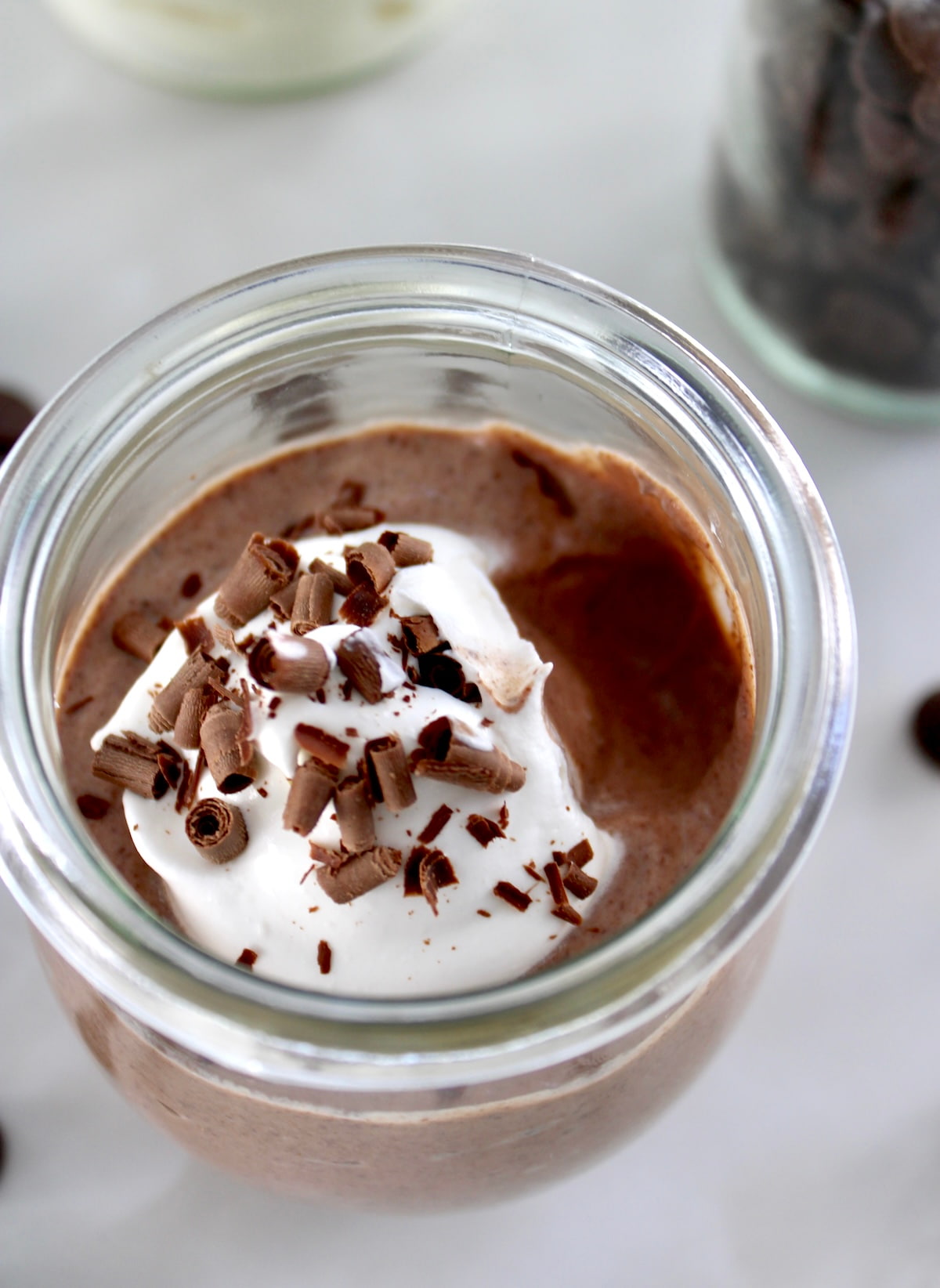 closeup of Ricotta Chocolate Mousse in open glass jar with whip cream and bite missing