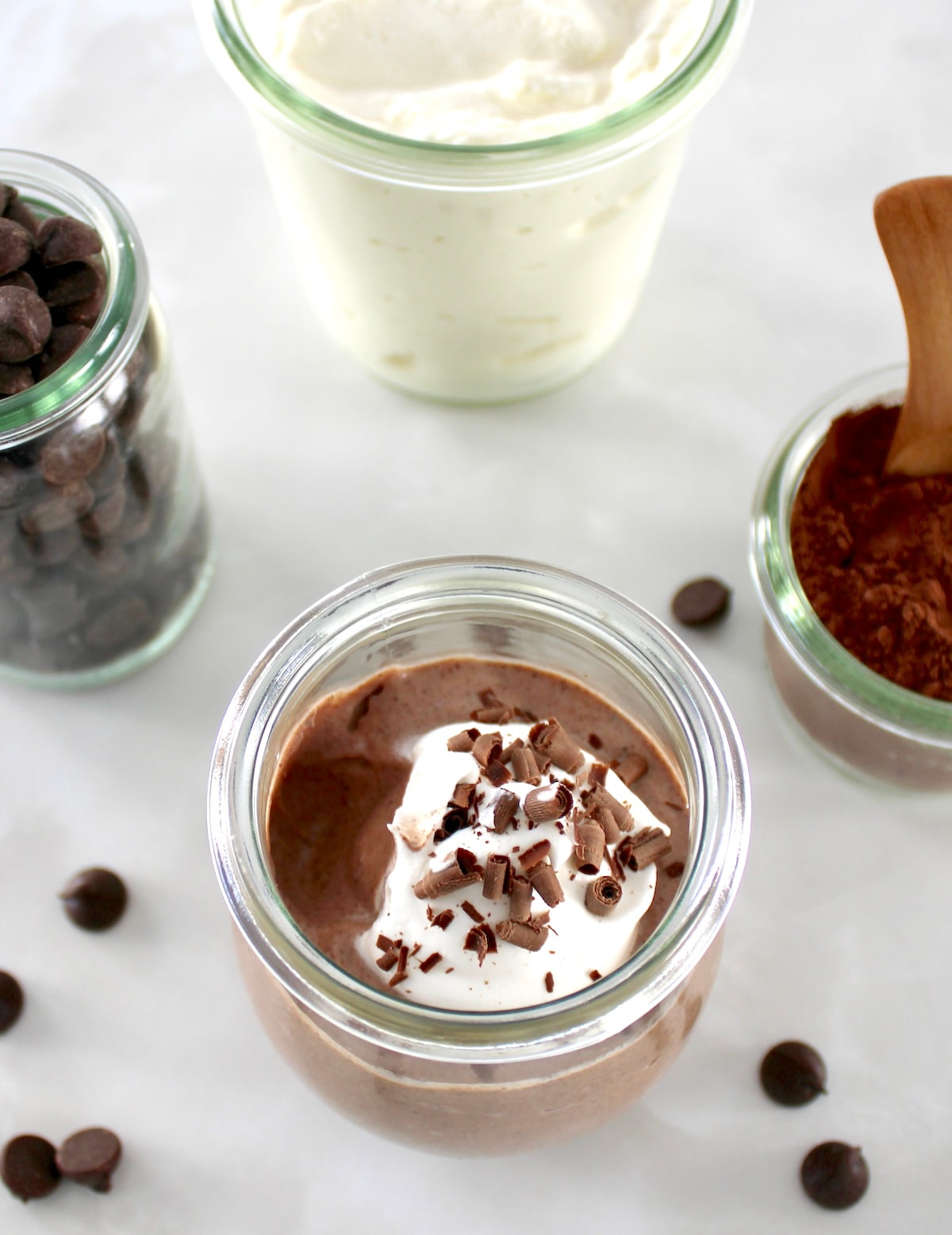 overhead view of Ricotta Chocolate Mousse in open glass jar with bite missing and whip cream on top