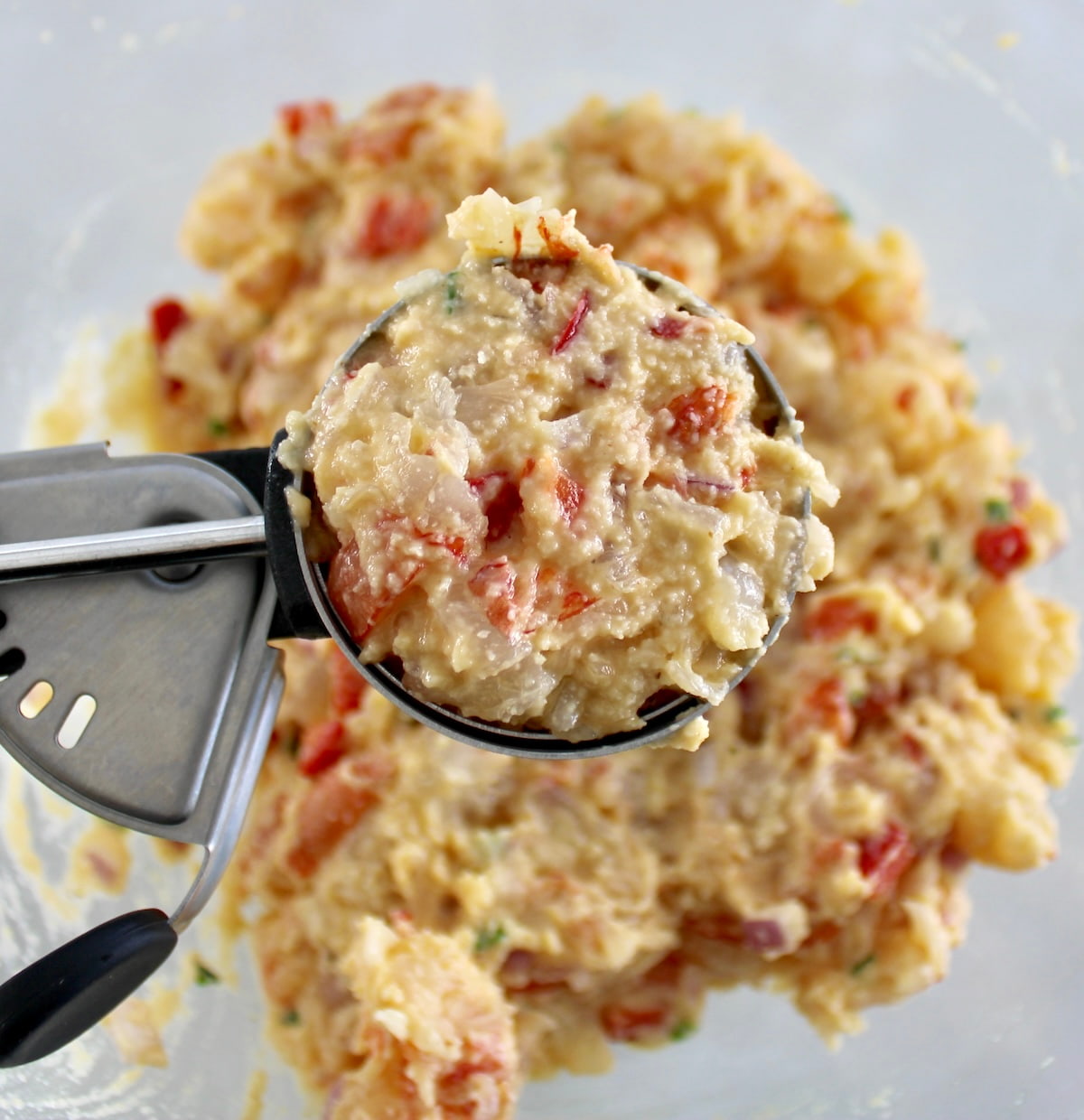 Shrimp Cakes batter in ice cream scoop held up over mixing bowl