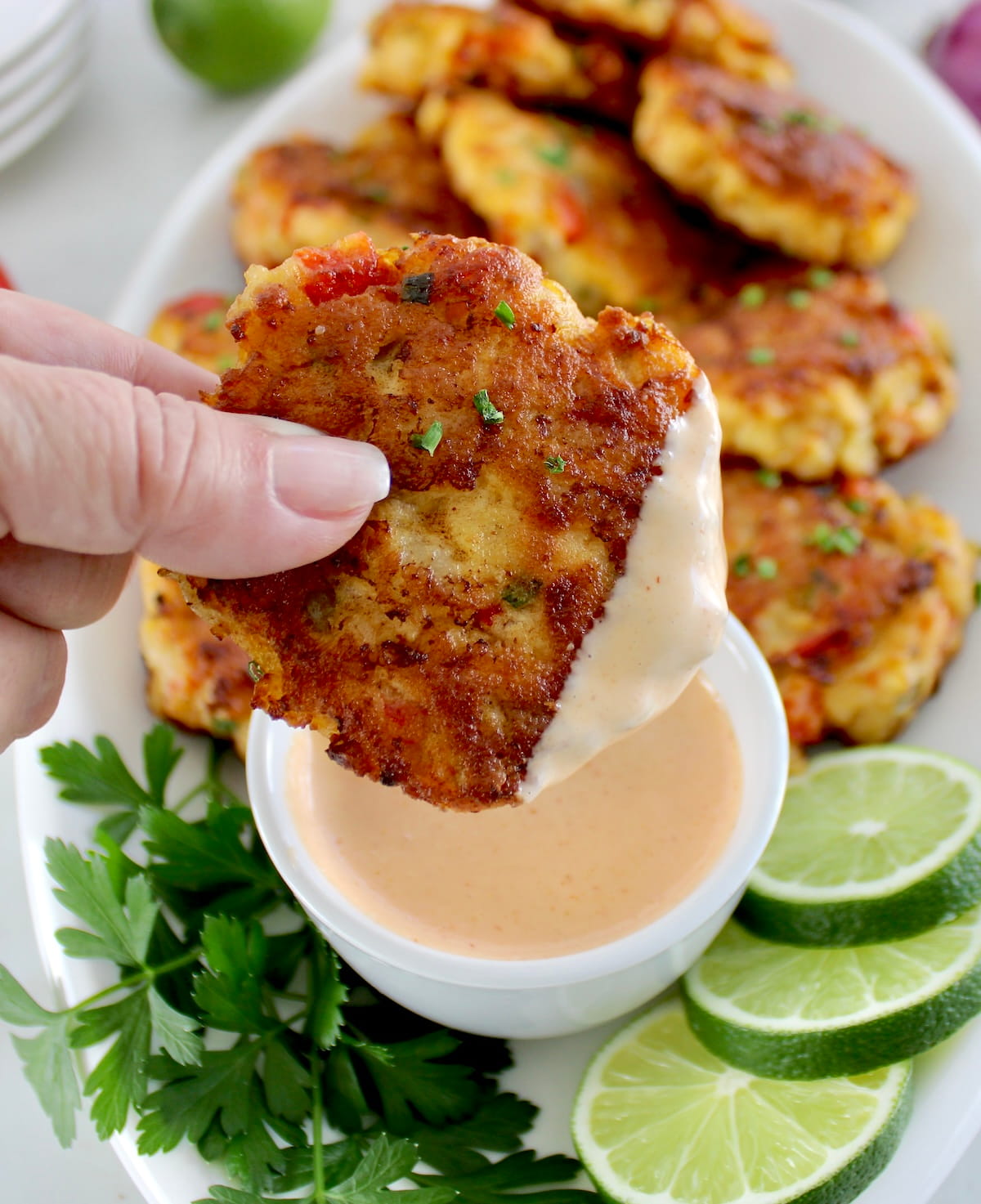 holding up Shrimp Cake dipped in spicy mayo 
