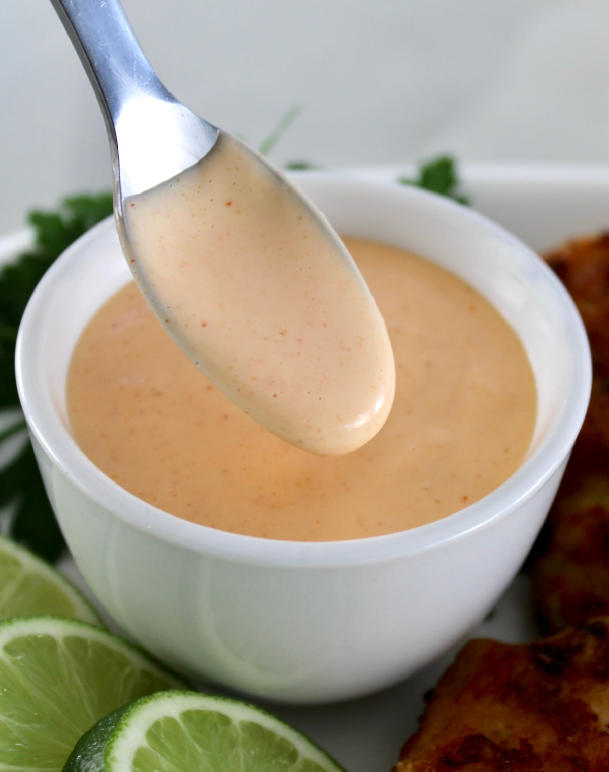 Spicy Mayo in spoon dripping into white bowl