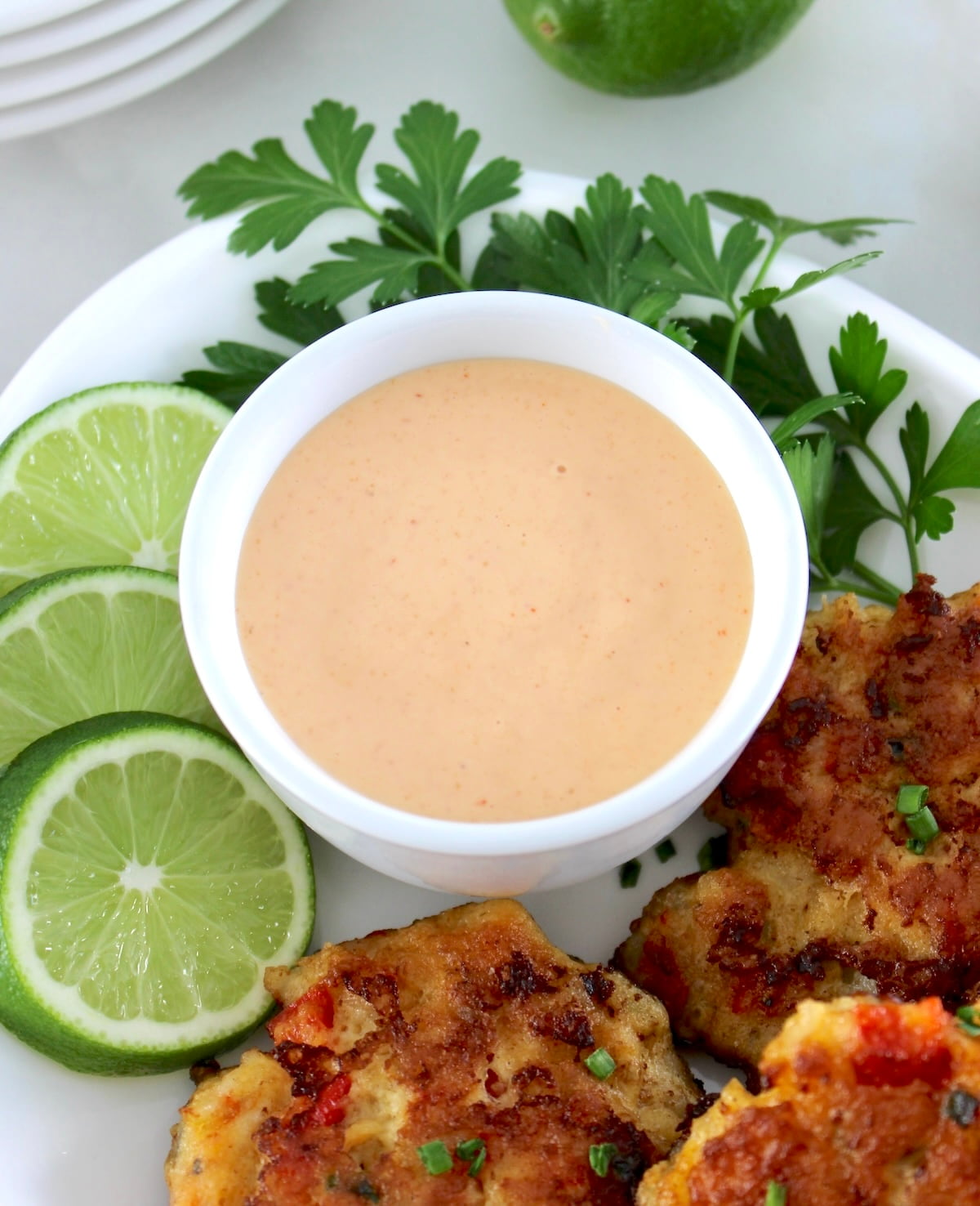 Spicy Mayo in white bowl with lime slices and patties on side