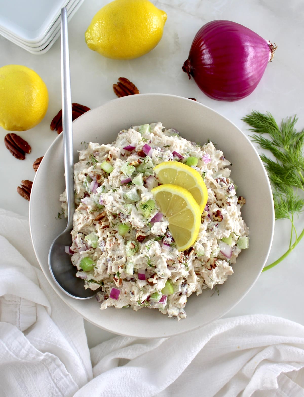 overhead view of Cottage Cheese Chicken Salad in white bowl with spoon on side and lemon slices on top