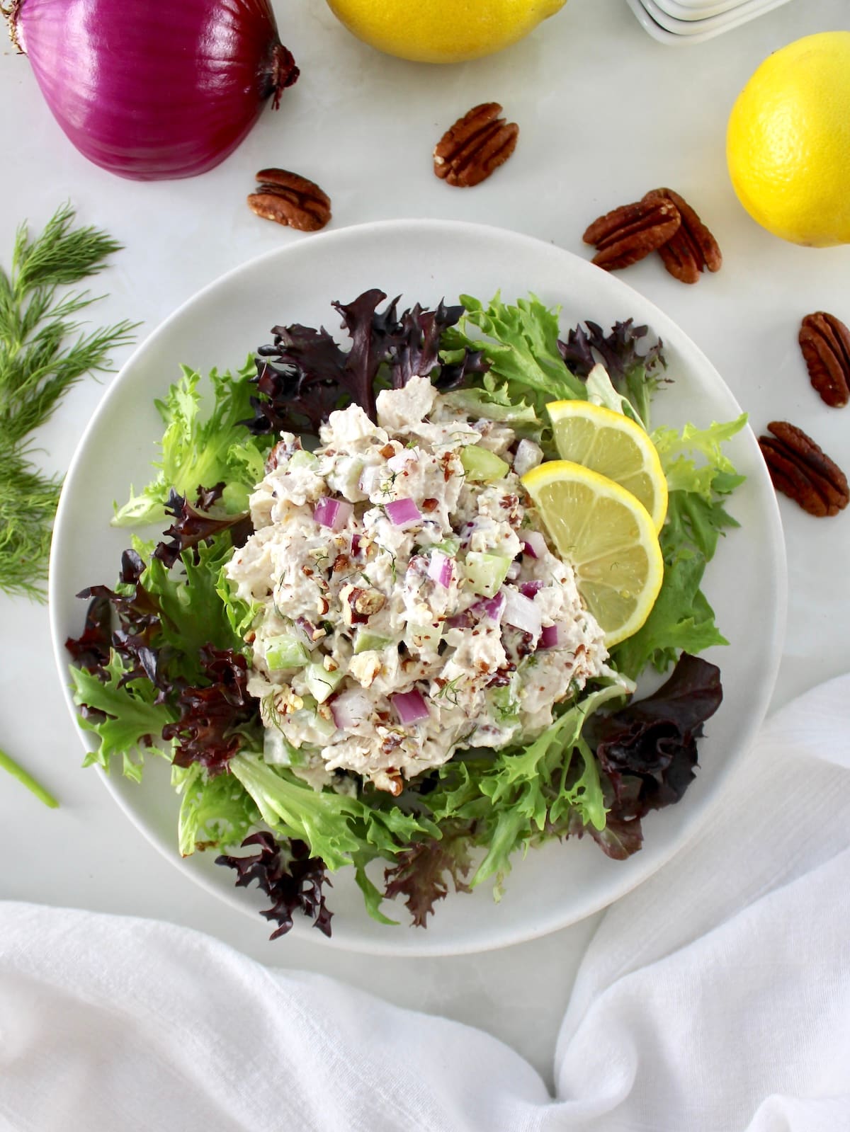 overhead view of Cottage Cheese Chicken Salad over mixed greens with lemon slices on side