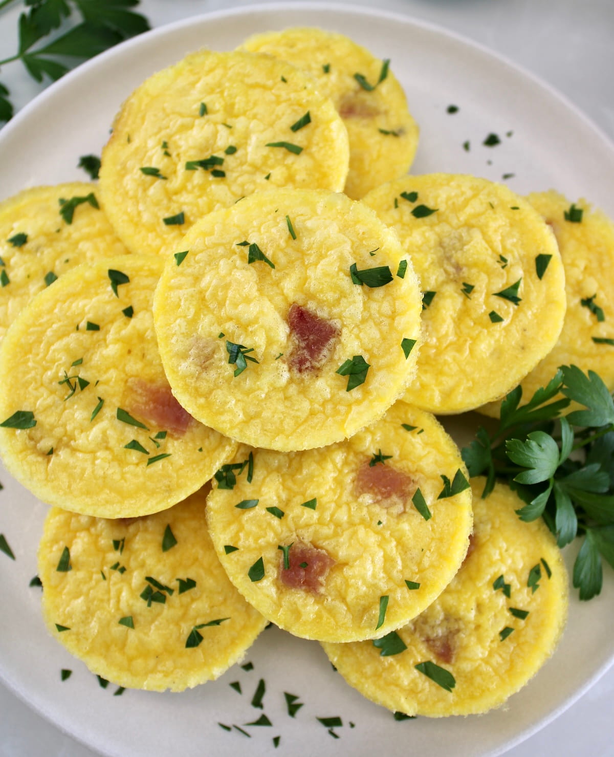 overhead view of Cottage Cheese and Ham Egg Bites with chopped parsley on white plate
