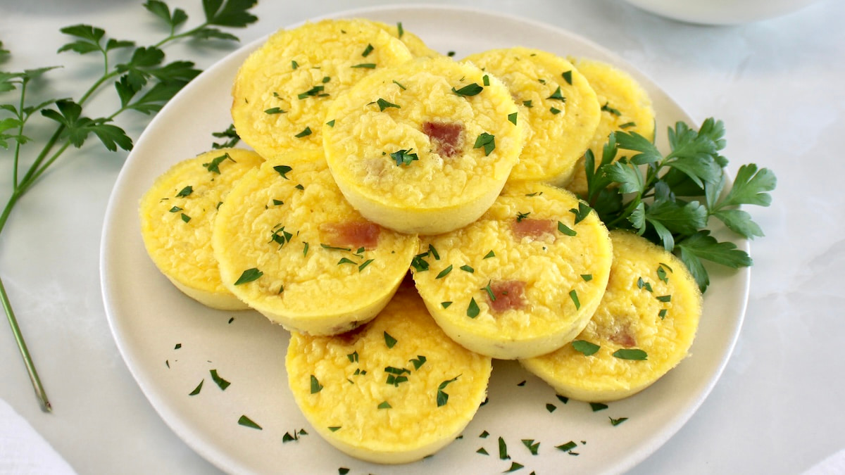 Cottage Cheese and Ham Egg Bites stacked up on white plate with chopped parsley