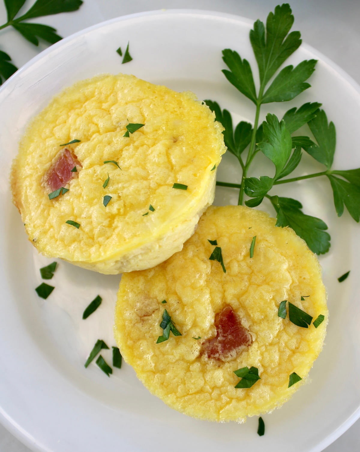 2 Cottage Cheese and Ham Egg Bites on white plate with parsley garnish